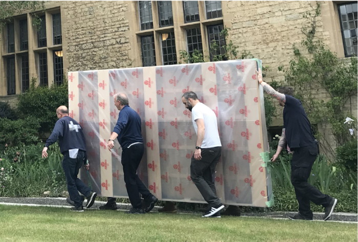 Art technicians carrying the painting across the garden