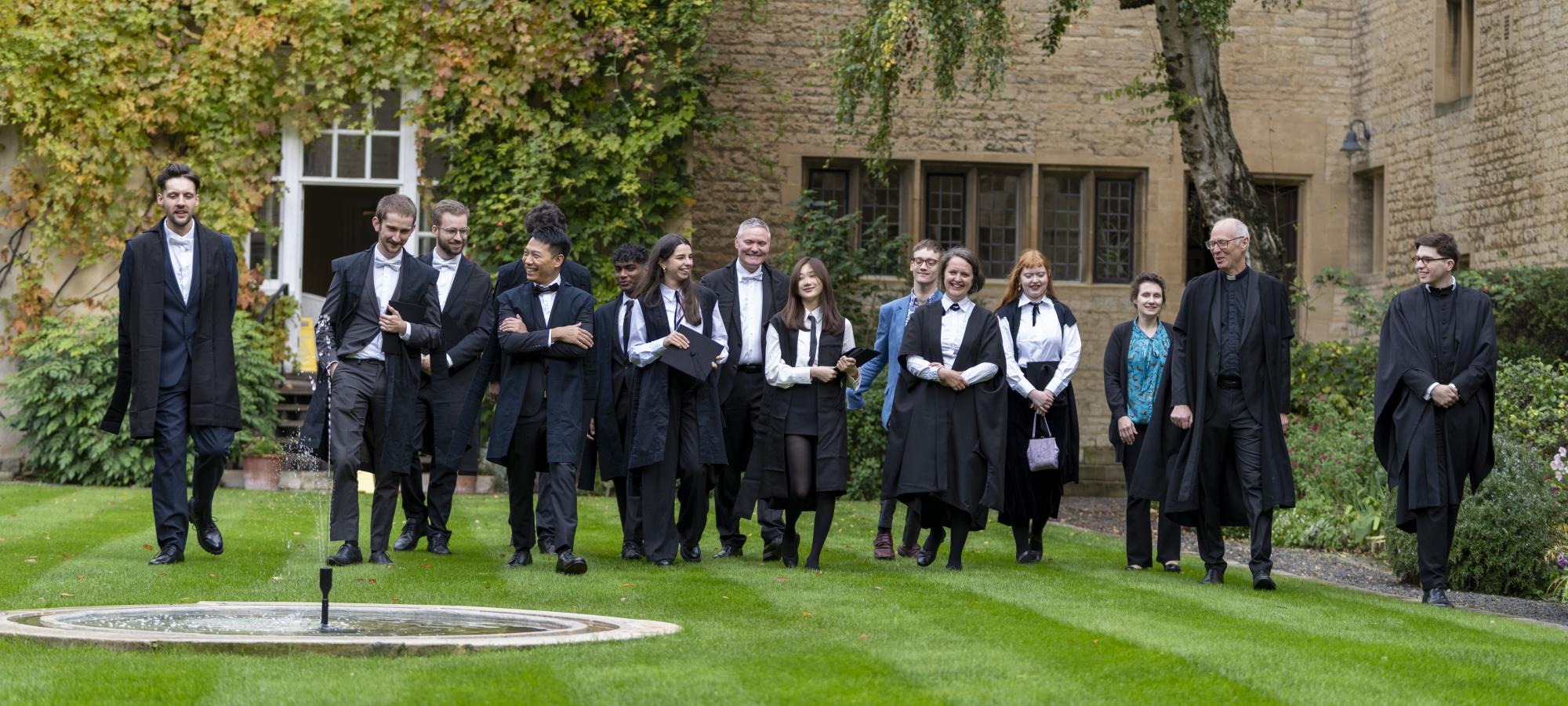 A group of students walking with the Master in the Campion Hall garden